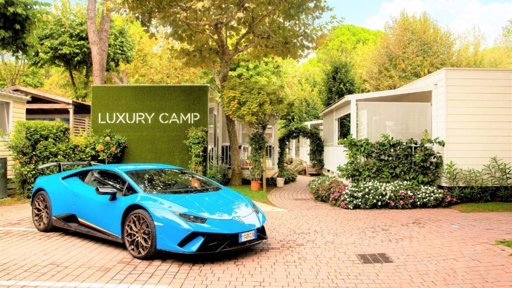 Eingang des Luxuscamps mit Lamborghini auf dem Parkplatz
